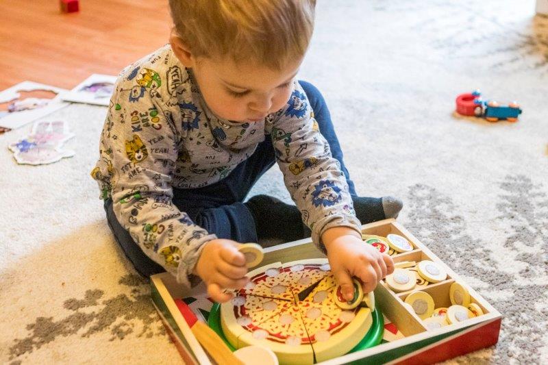 Rex playing with the Pizza Party Wooden Food set from Melissa and Doug