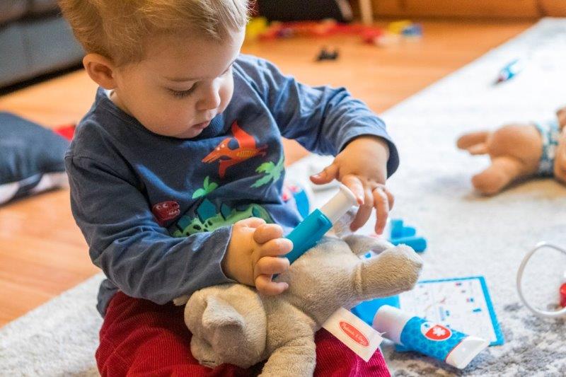 Rex pretending to give the cat an injection from the Melissa and Doug Pet Vet Play Set