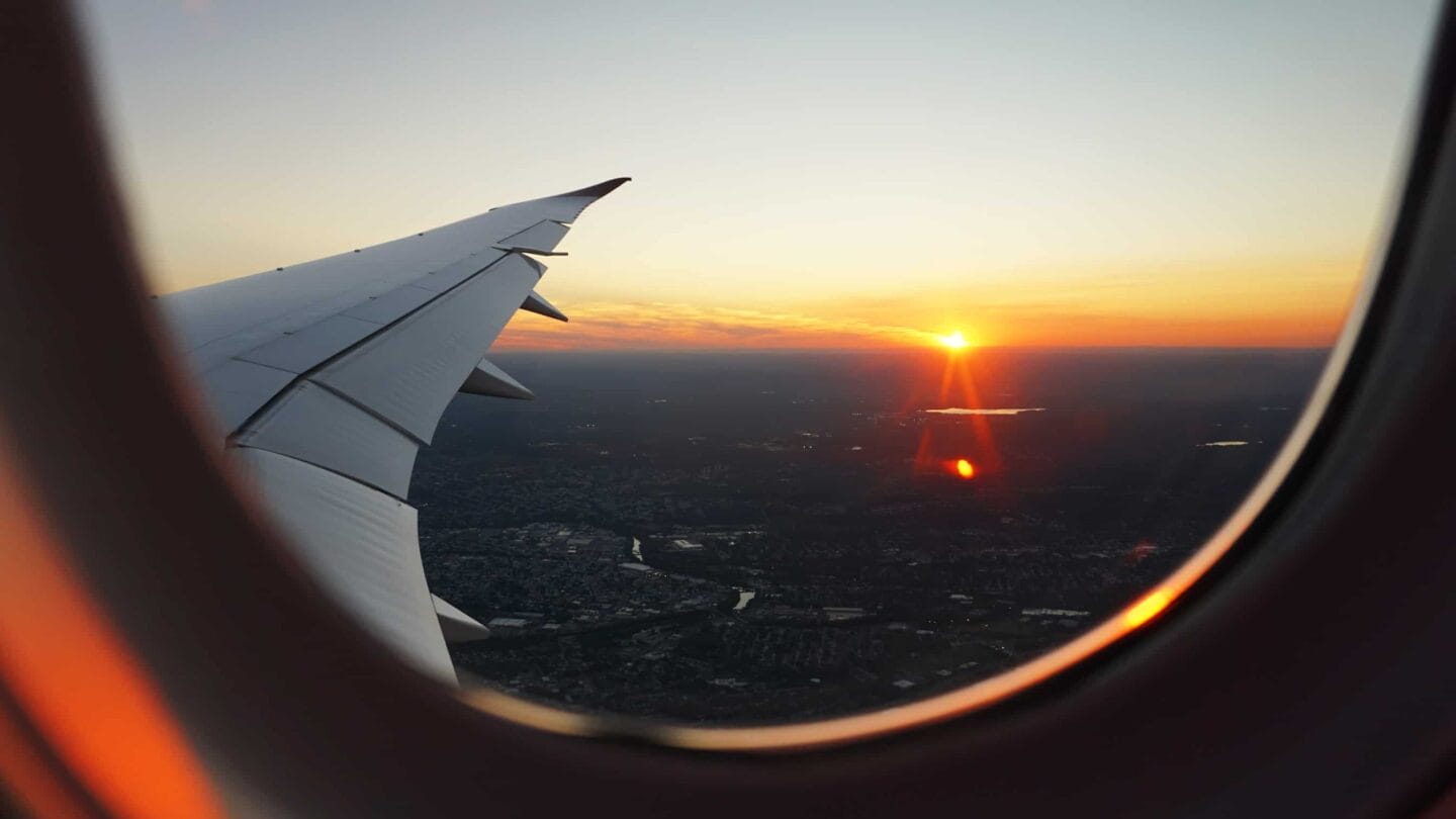 View of the plane wing and bright red sunset through window