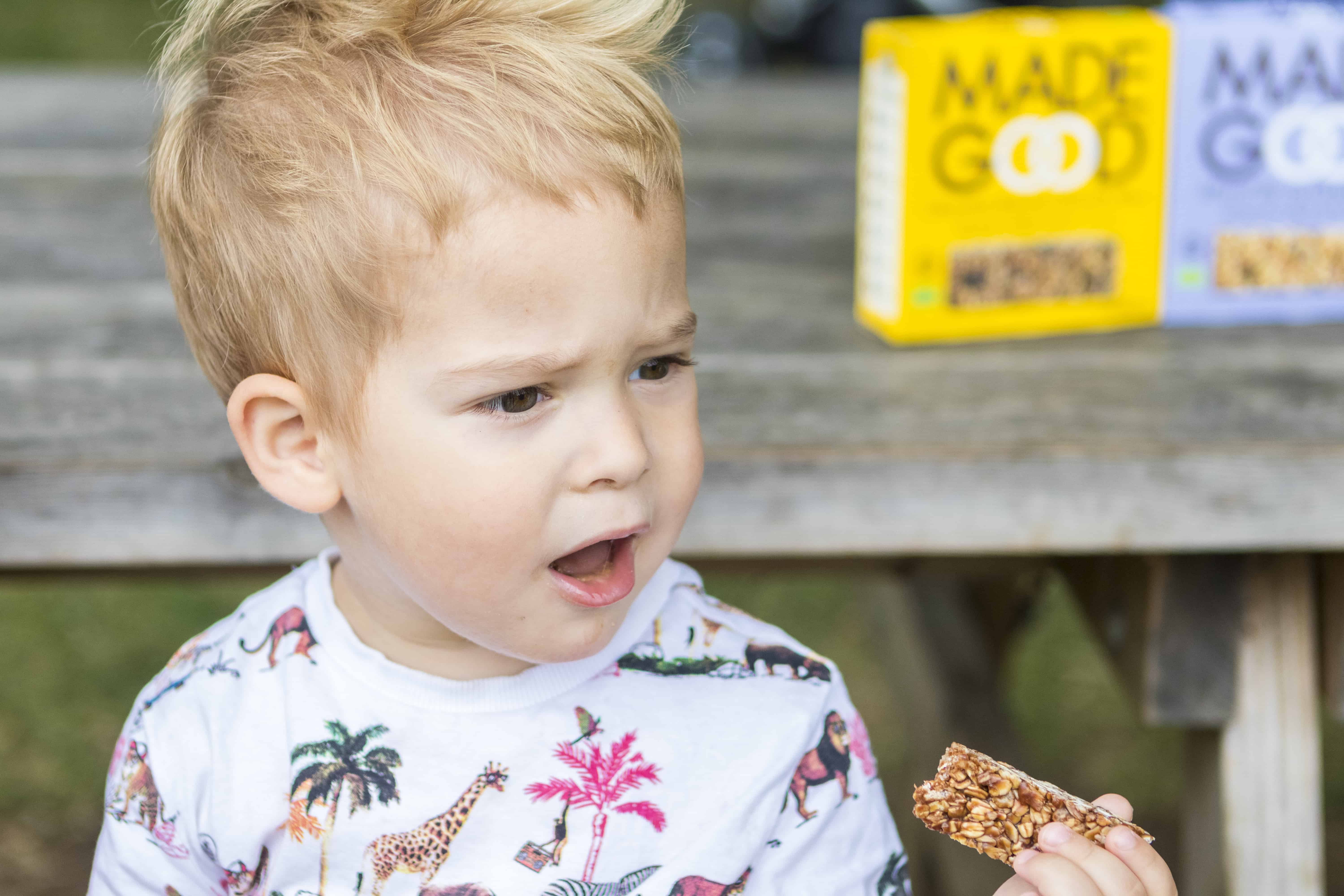 A small boy eating a MadeGood bar
