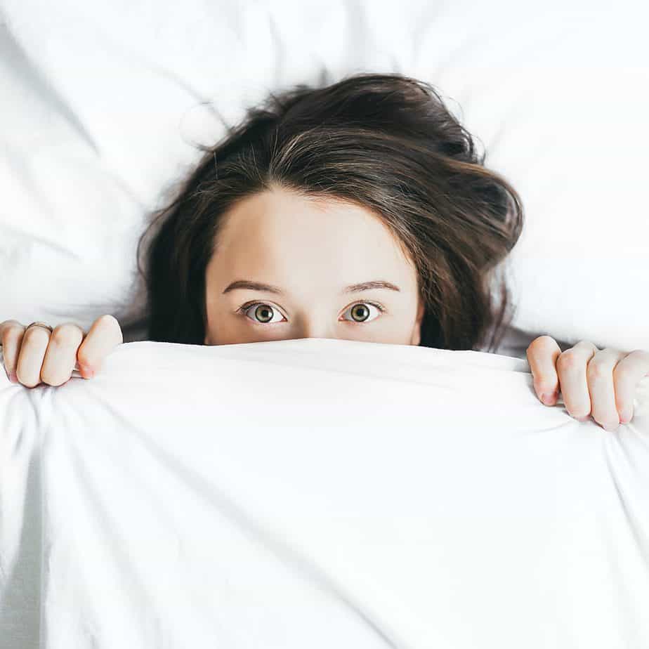 A woman peeping out from her bed covers