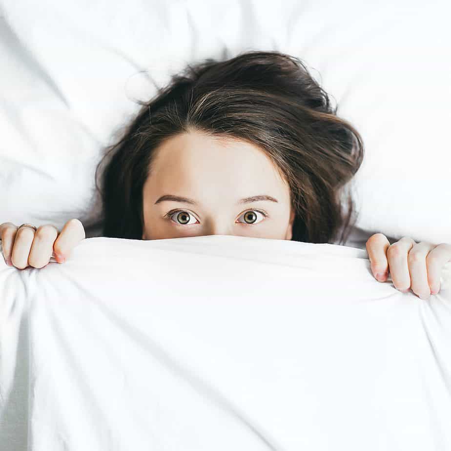 A woman peeping out from her bed covers