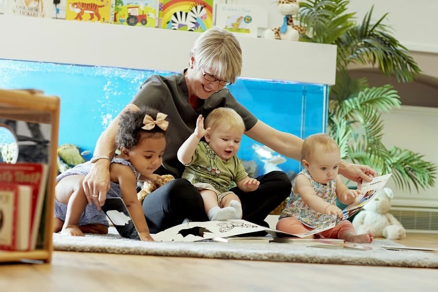 Young children looking at a book with their carer for World Book Day