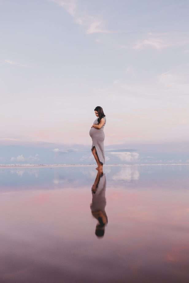 Pregnant women standing on a beach on her own