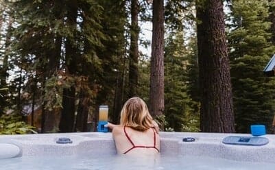 A woman relaxing in a hot tub in a forest after exercise