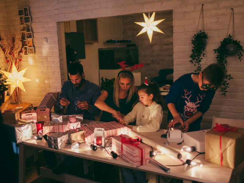 a family of mum, dad, son and daughter wrapping Christmas gifts